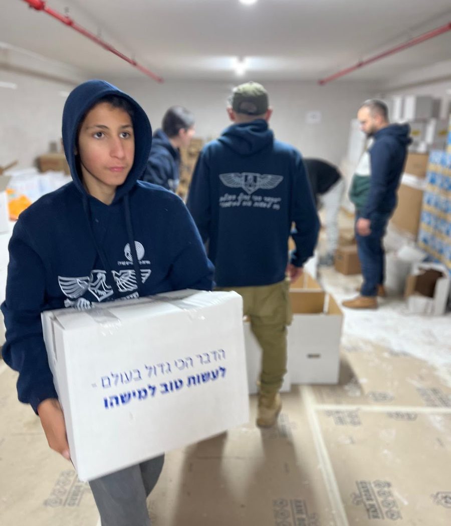 נער מסח"י נושא קרטון מזון שעליו כתוב "הדבר הכי גדול בעולם – לעשות טוב למישהו"